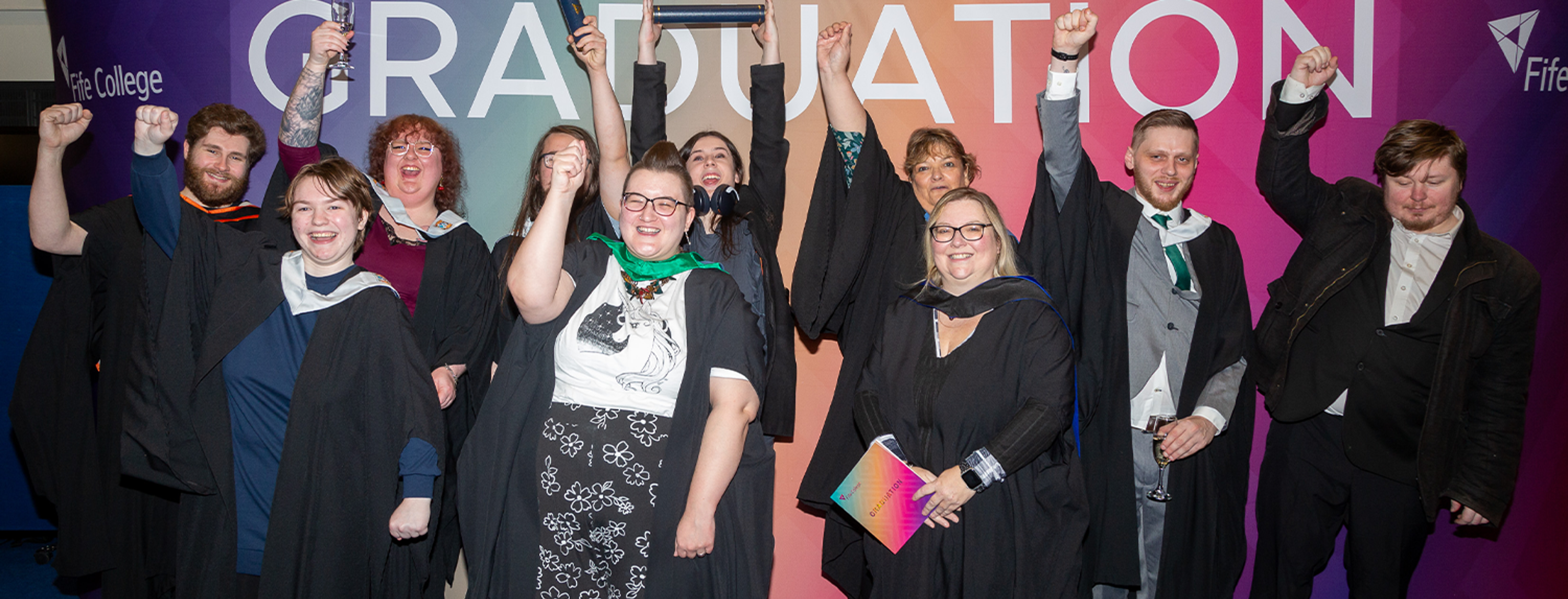 group of graduates holding scrolls smiling at camera
