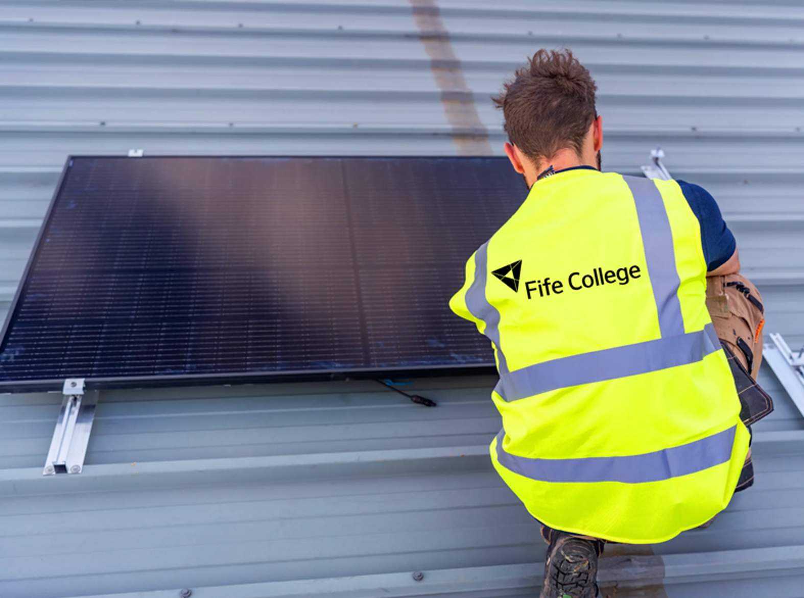 solar panel being fitted by student wearing fife college high vis