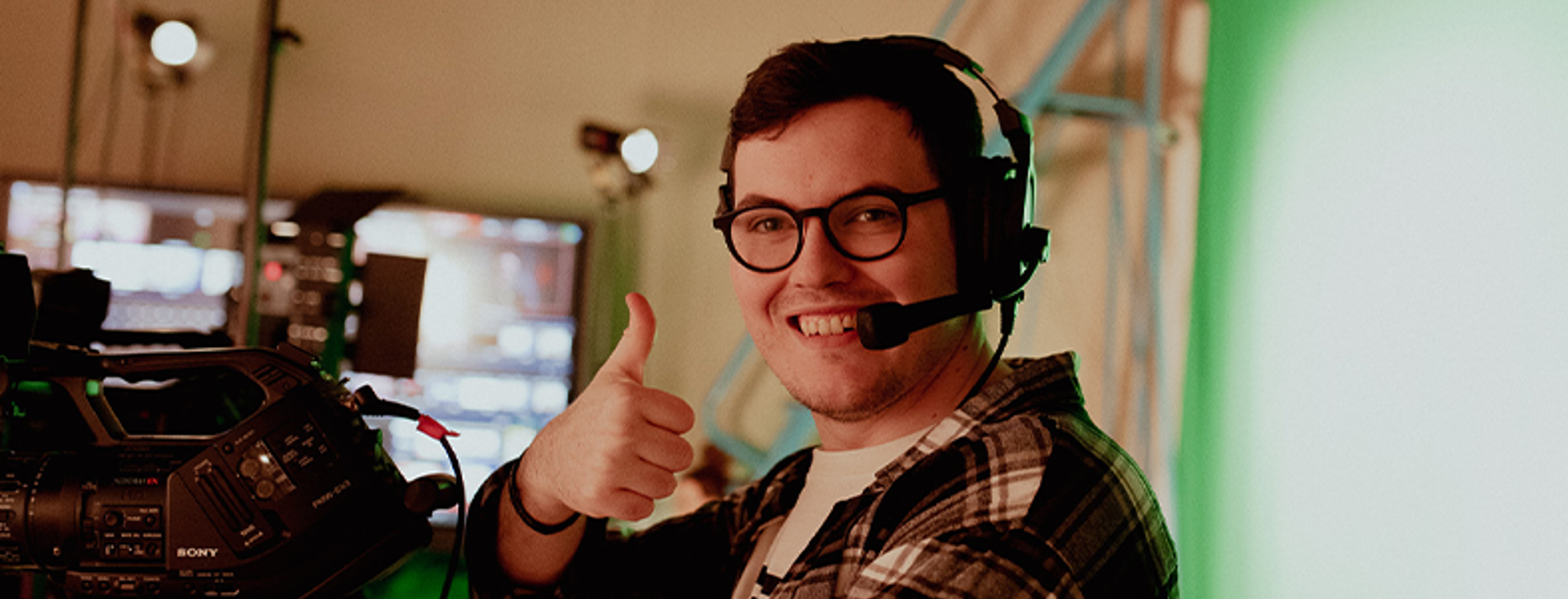 broadcast media student holding thumbs up smiling at camera