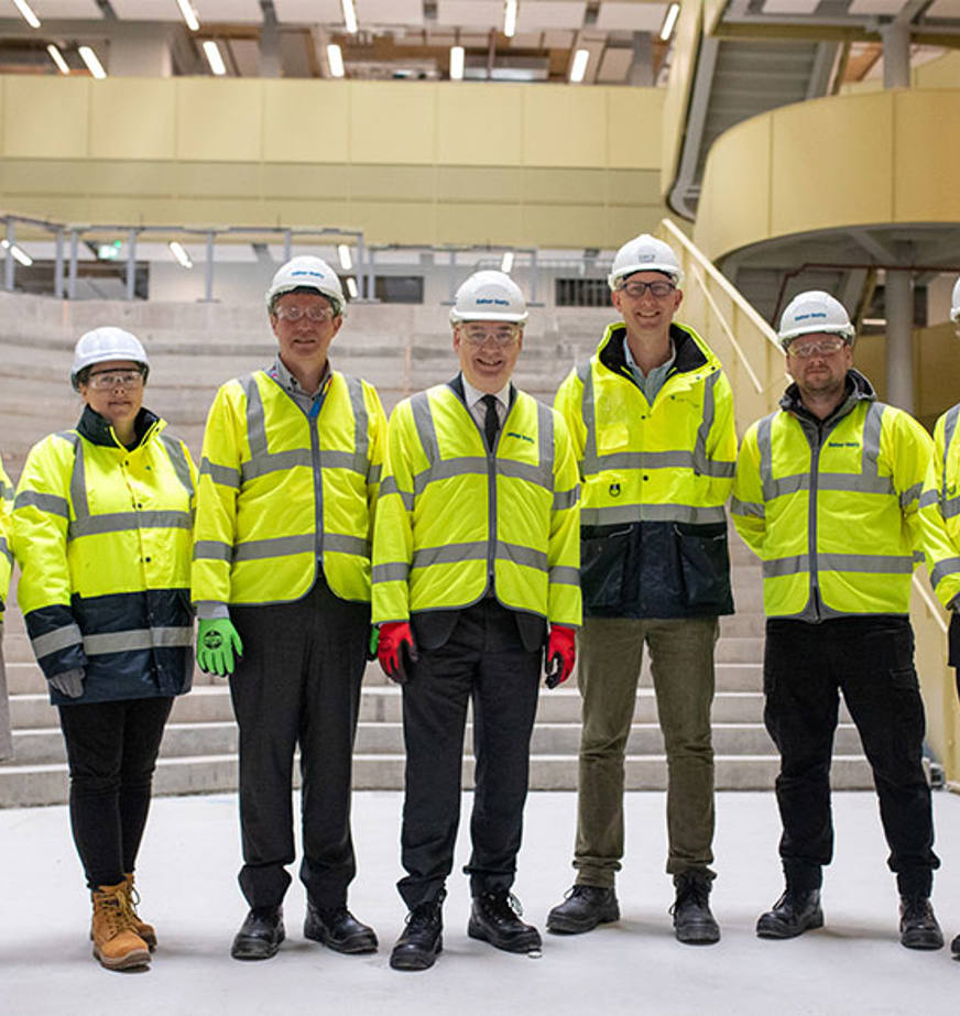 A group of people wearing personal proective equipment standing in a builing
