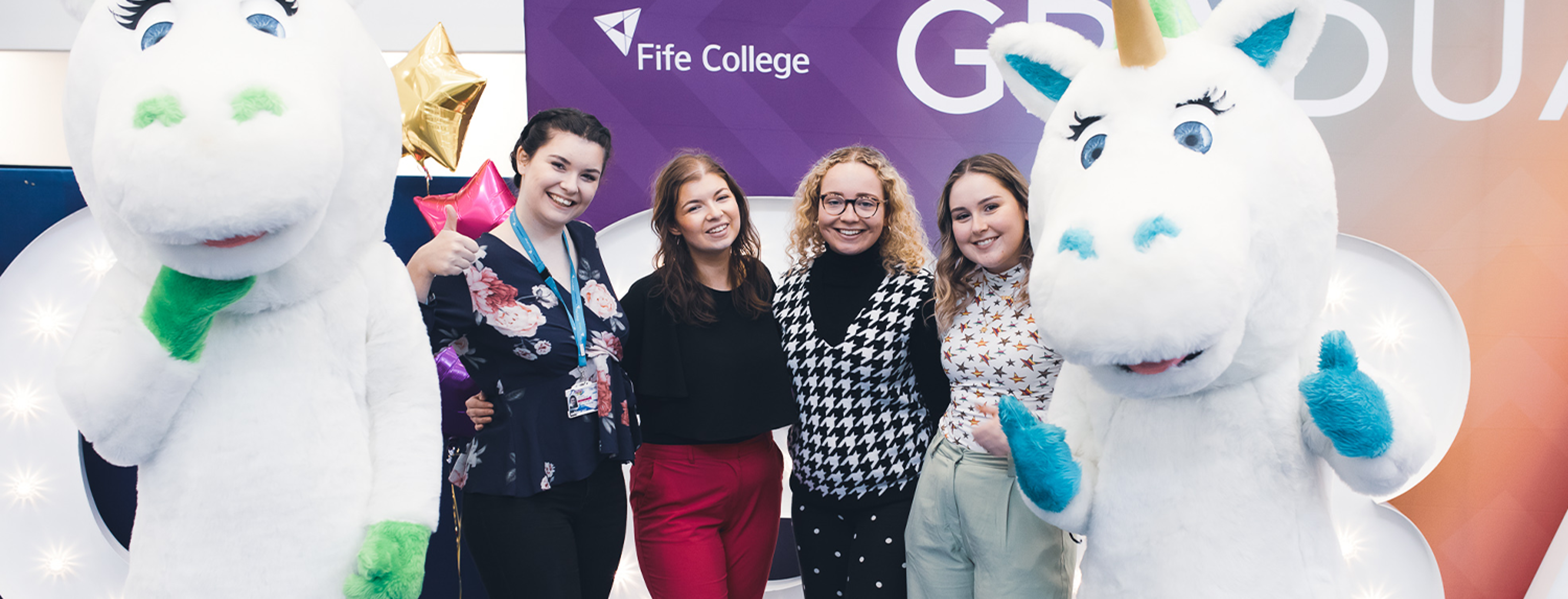 group of fife college staff members with two unicorn mascots at graduation